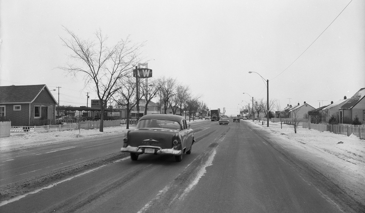 A wide street with homes on both sides and an A&W restaurant further up.